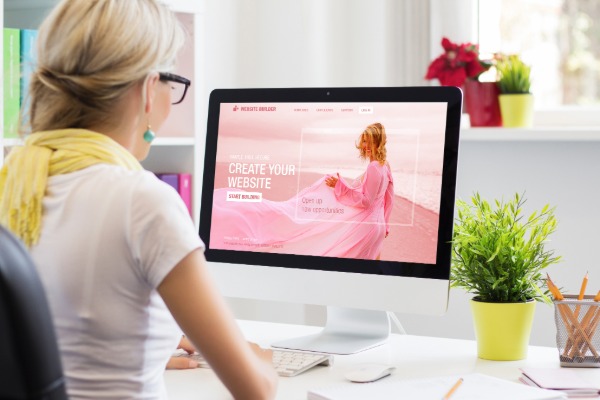 woman sitting at desk viewing a website on a desk top computer